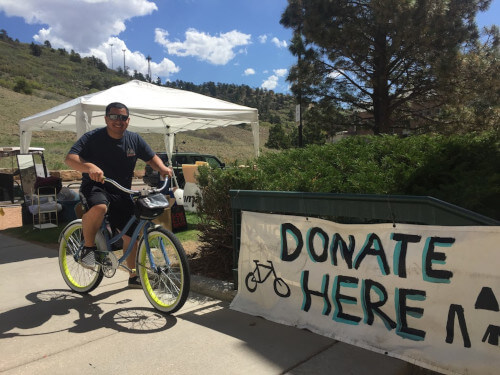 Student on bike in front of donation sign