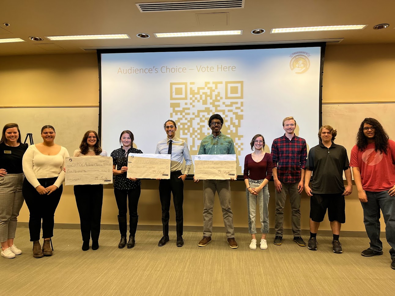 students in a row holding winner's checks