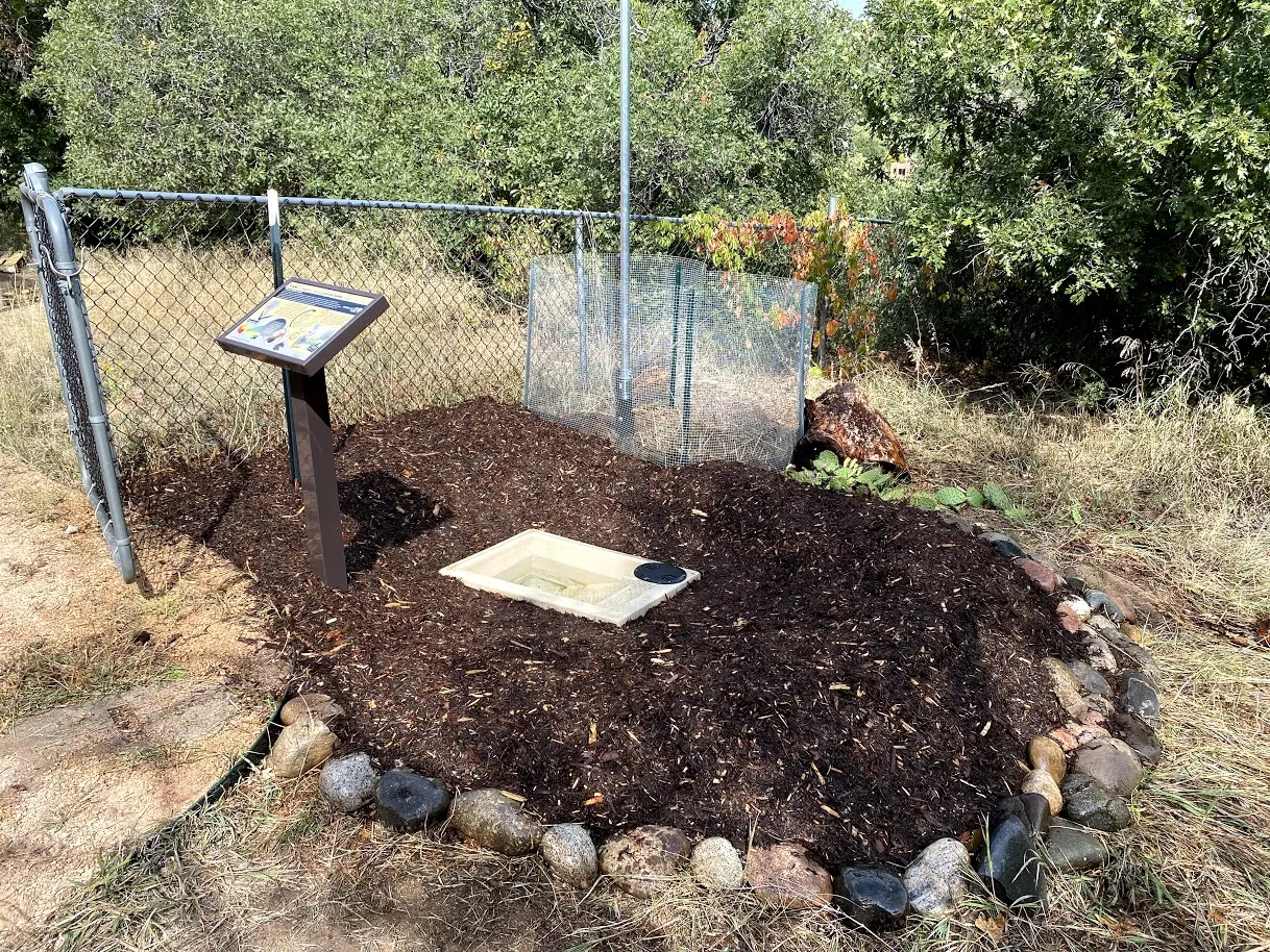 guzzler in the ground with brown mulch around it