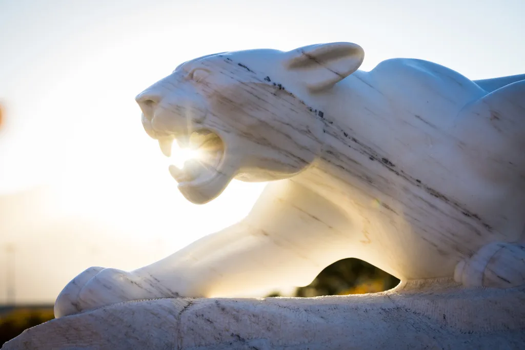 UCCS Mountain Lion Statue with harsh sun glaring into camera lens from behind lion head in the background